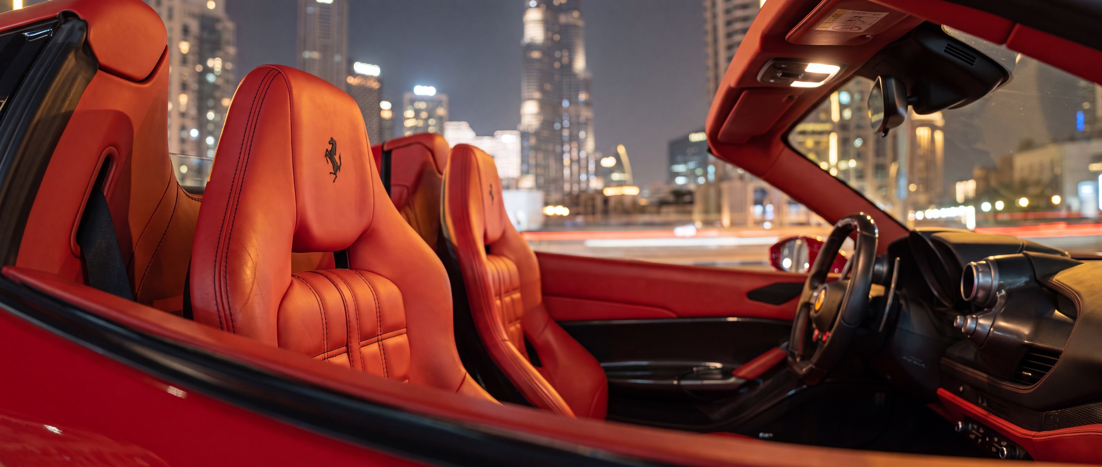 Ferrari F8 Tributo Spyder red leather seat and headrest detail, Downtown Dubai skyline at night through the window
